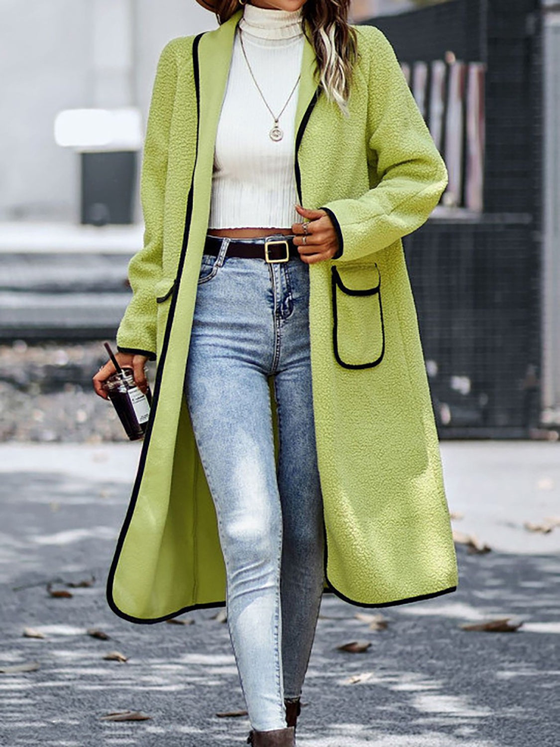 Lime teddy coat with contrast trim detailing and pocket, worn open over a white turtleneck and jeans.