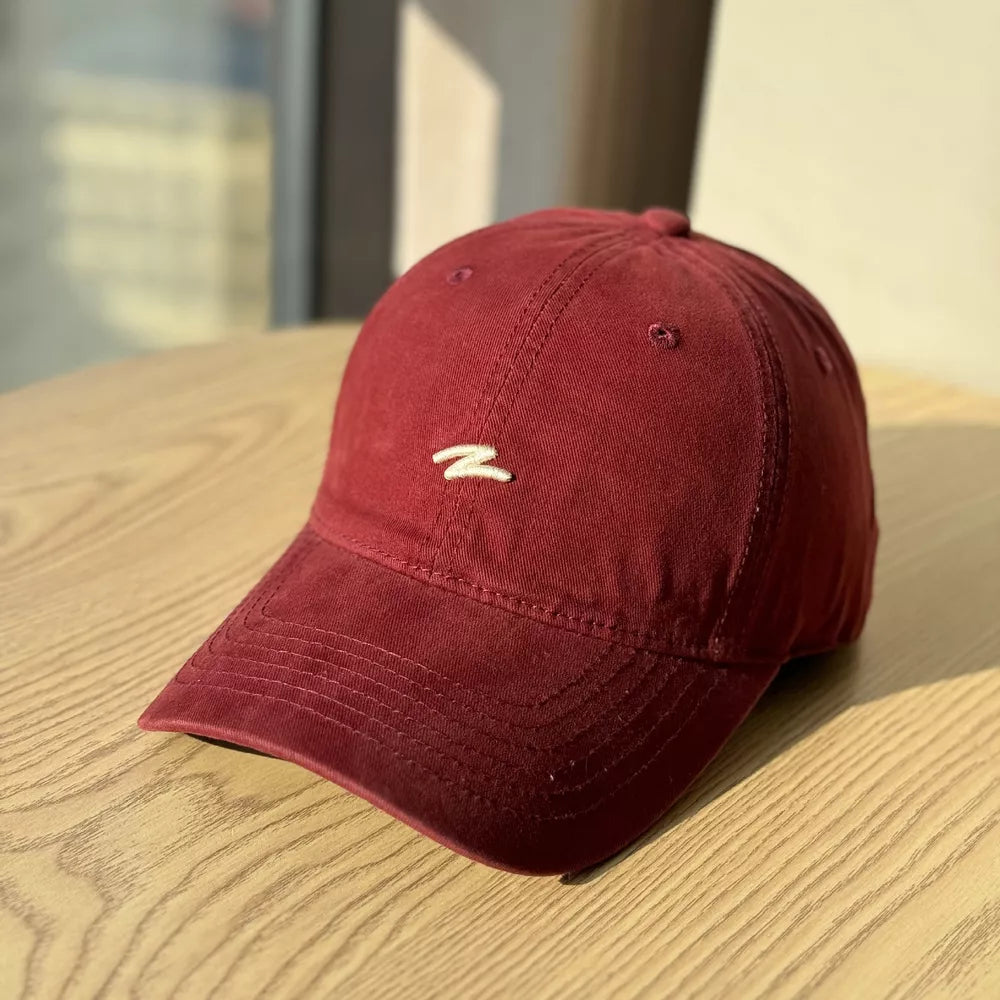 Distressed vintage cotton baseball hat in wine red with embroidered detail and curved brim.