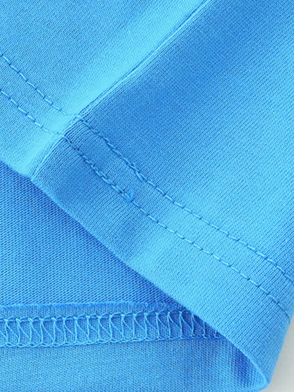 Blue cotton t-shirt detail showing stitching and fabric texture.