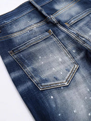 Men's dark blue distressed slim-fit jeans with paint splatter detail.