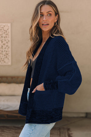 Navy textured open-front knit cardigan with pockets and balloon sleeves.