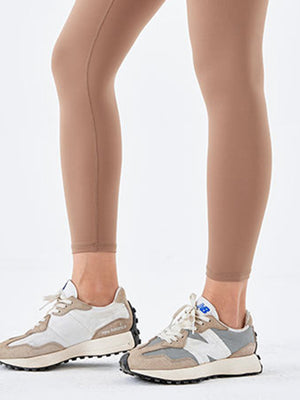 Caramel high-waist leggings with a seamless look, paired with athletic sneakers.