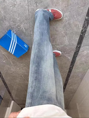 Men's light blue vintage wash straight-leg jeans styled with red sneakers.