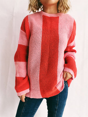 Vertical stripe waffle knit sweater in pink and orange-red with crew neck and long sleeves.