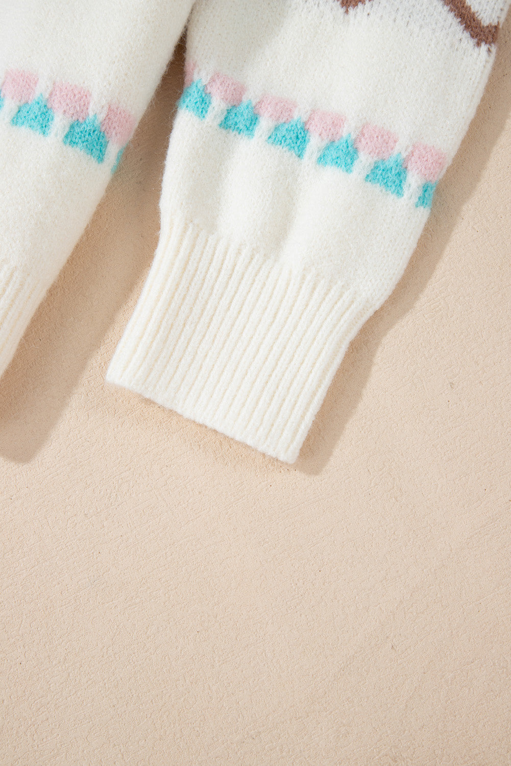 White acrylic knit sweater with pastel geometric pattern and ribbed cuffs.