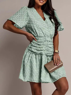 Light green textured V-neck ruched mini dress with short sleeves and a ruffled hem.