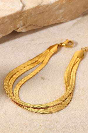 Gold triple herringbone chain bracelet with a flat, flexible design.