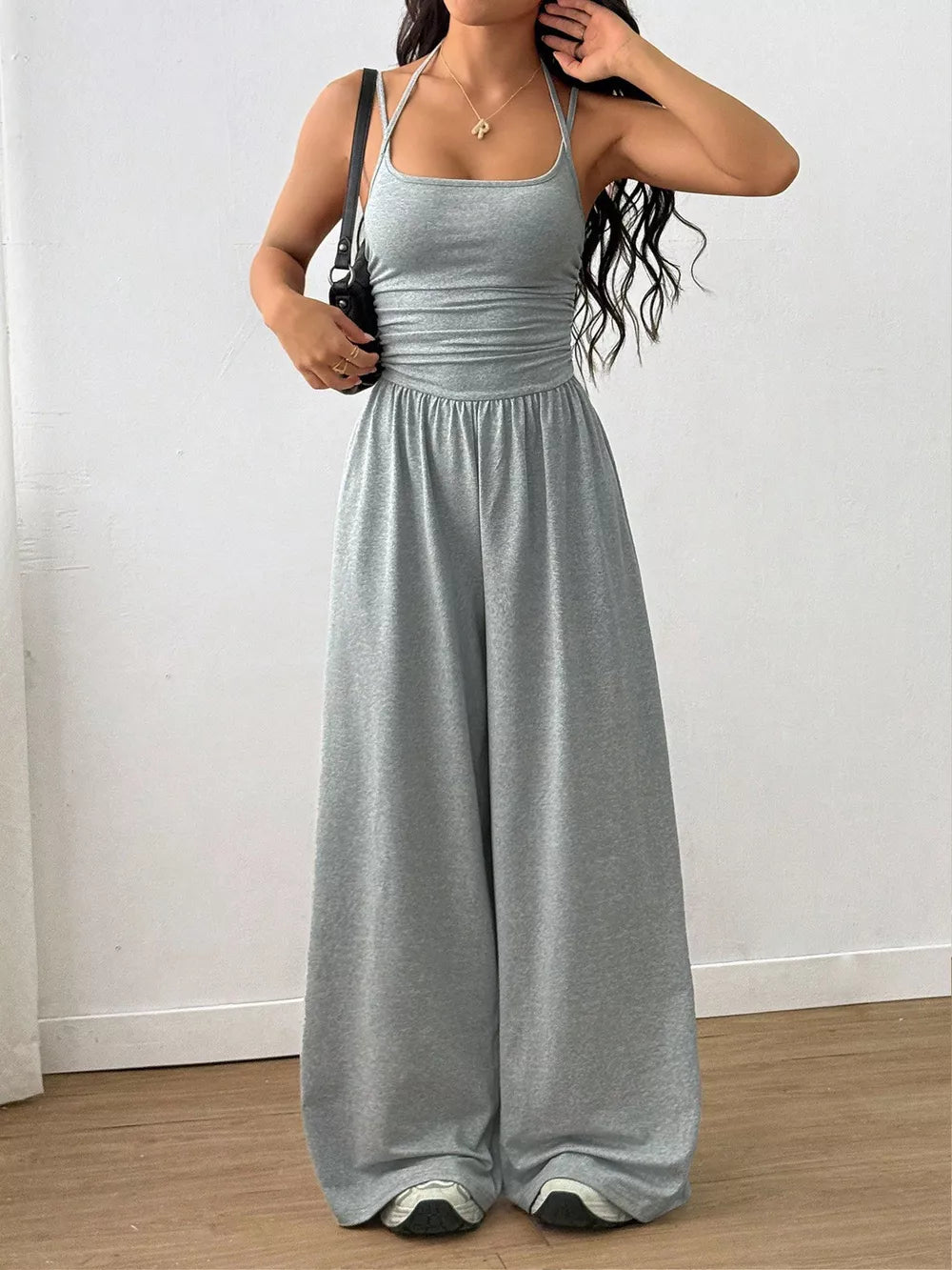 Gray wide-leg jumpsuit with ruched waist and spaghetti straps.