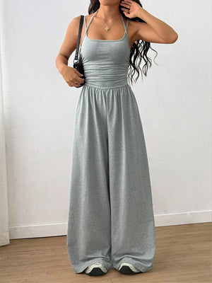 Gray wide-leg jumpsuit with ruched waist and spaghetti straps.
