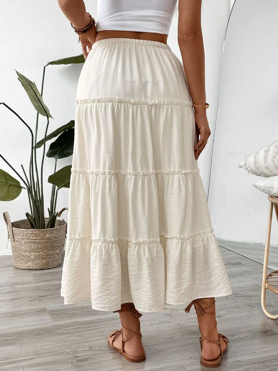 Cream tiered midi skirt with drawstring waist and ruffled seams.