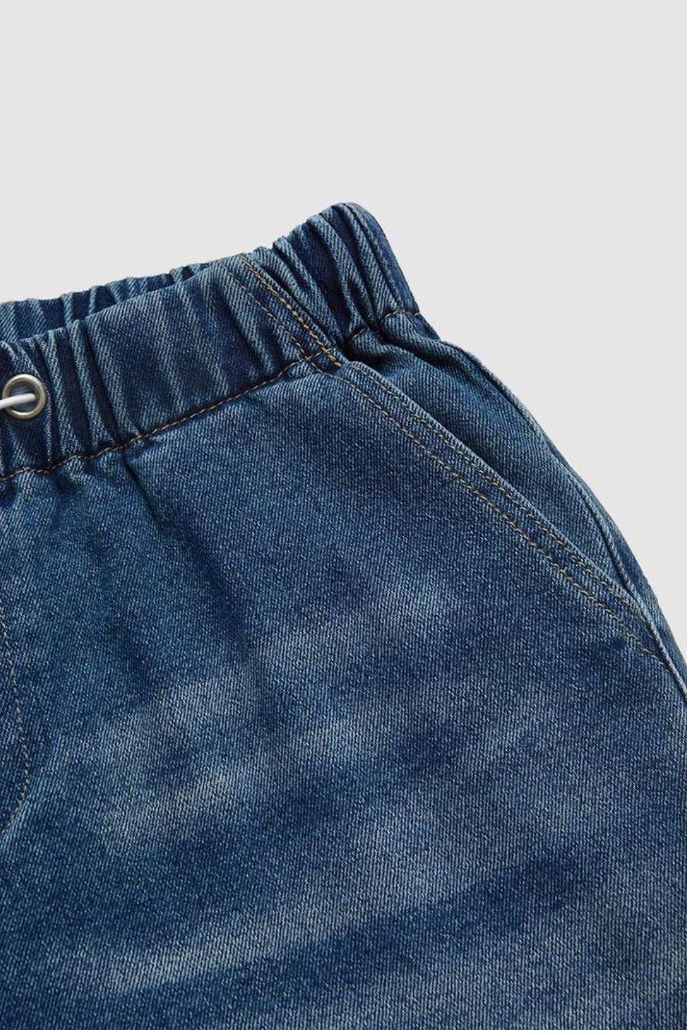 Elastic waist palazzo jeans in medium wash denim with drawstring detail and pockets.