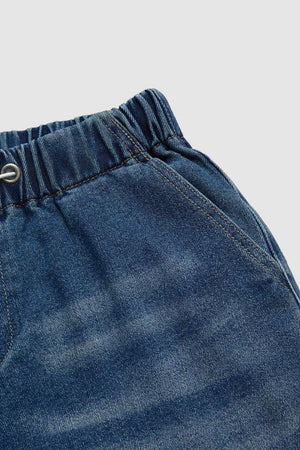 Elastic waist palazzo jeans in medium wash denim with drawstring detail and pockets.