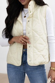 Quilted stand collar vest in ivory with snap closures.