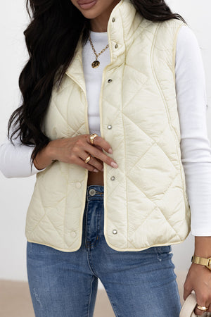 Quilted stand collar vest in ivory with snap closures.