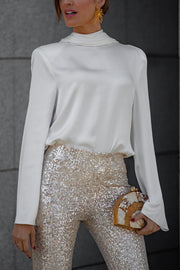 White silk blouse with draped back and long sleeves worn with sequin pants