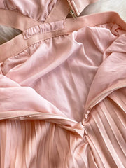 Pink pleated maxi dress with cutout detail and zipper closure.