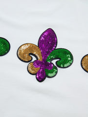 White cotton t-shirt with Mardi Gras fleur de lis sequin embellishments in purple, gold, and green.