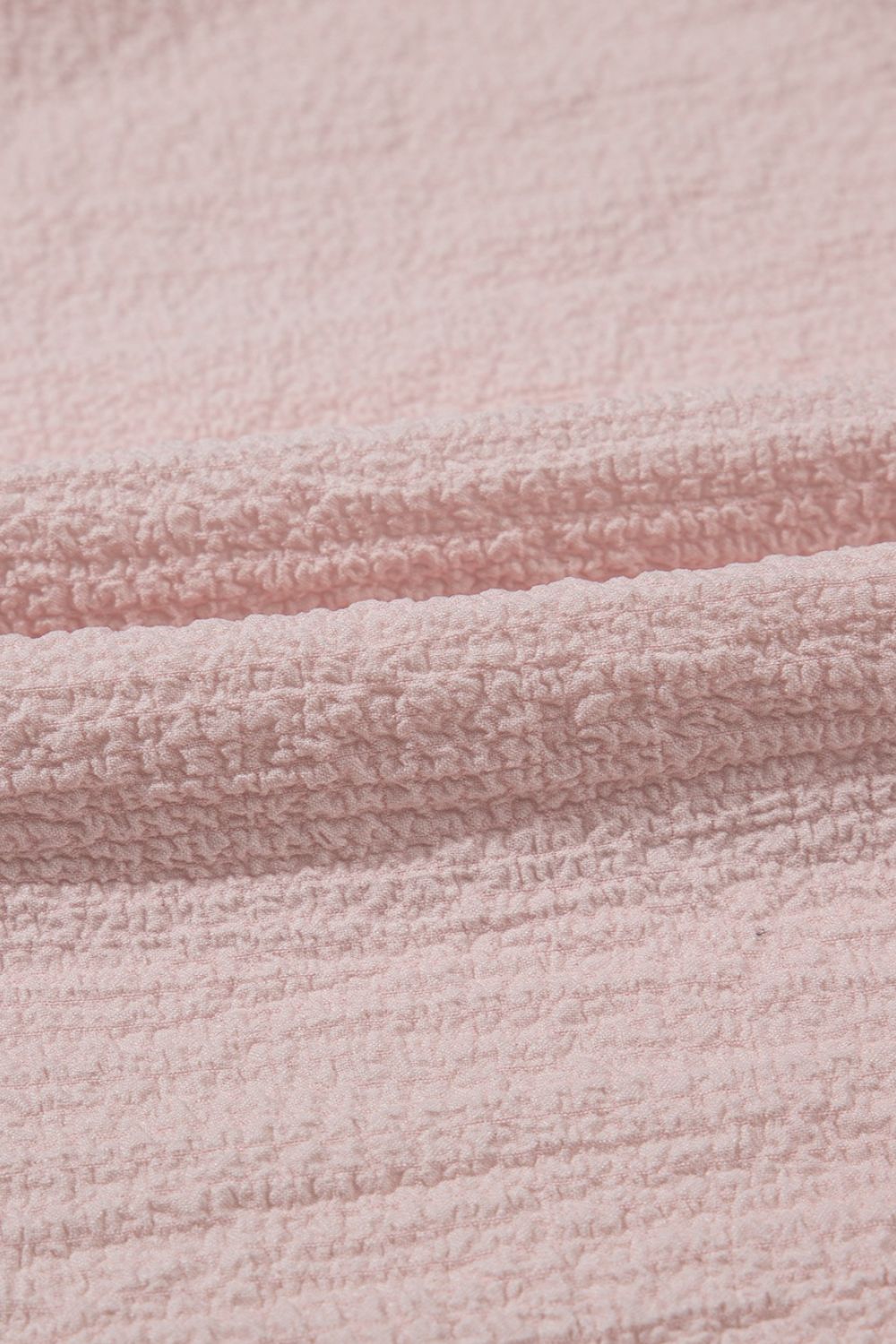 Blush pink textured blouse with ruffle sleeves and bow detail close-up