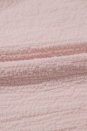 Blush pink textured blouse with ruffle sleeves and bow detail close-up