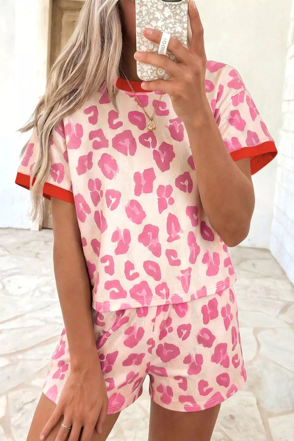 Pink leopard print polyester two-piece set with red trim on t-shirt and shorts.