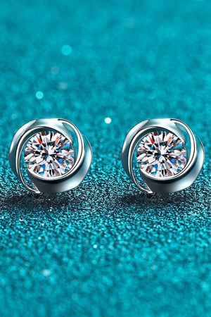 Silver halo stud earrings with clear crystals on a textured blue background.