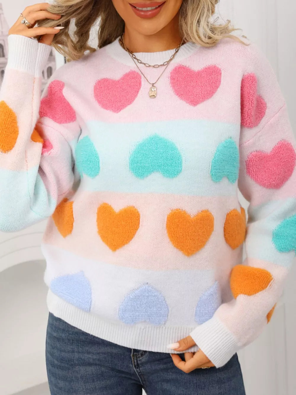 Charming heart-embellished fuzzy knit sweater with color block stripes and crew neck.