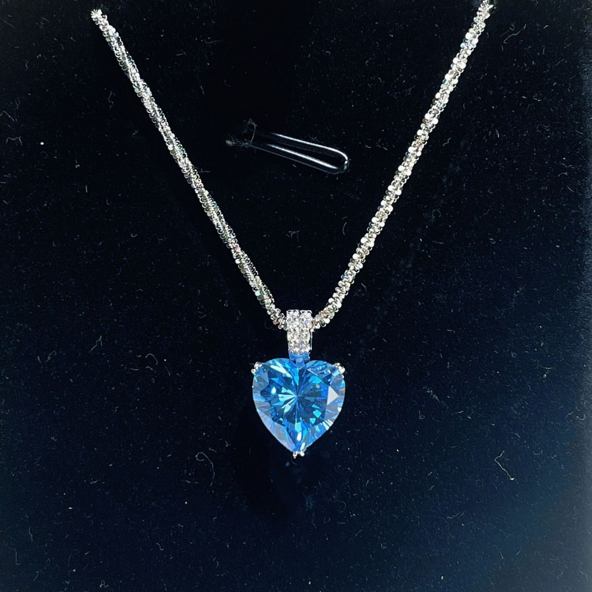 Dazzling heart pendant necklace in silver with a blue stone and delicate chain.