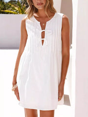 White sleeveless mini dress with tie-front neckline and subtle vertical pleats.