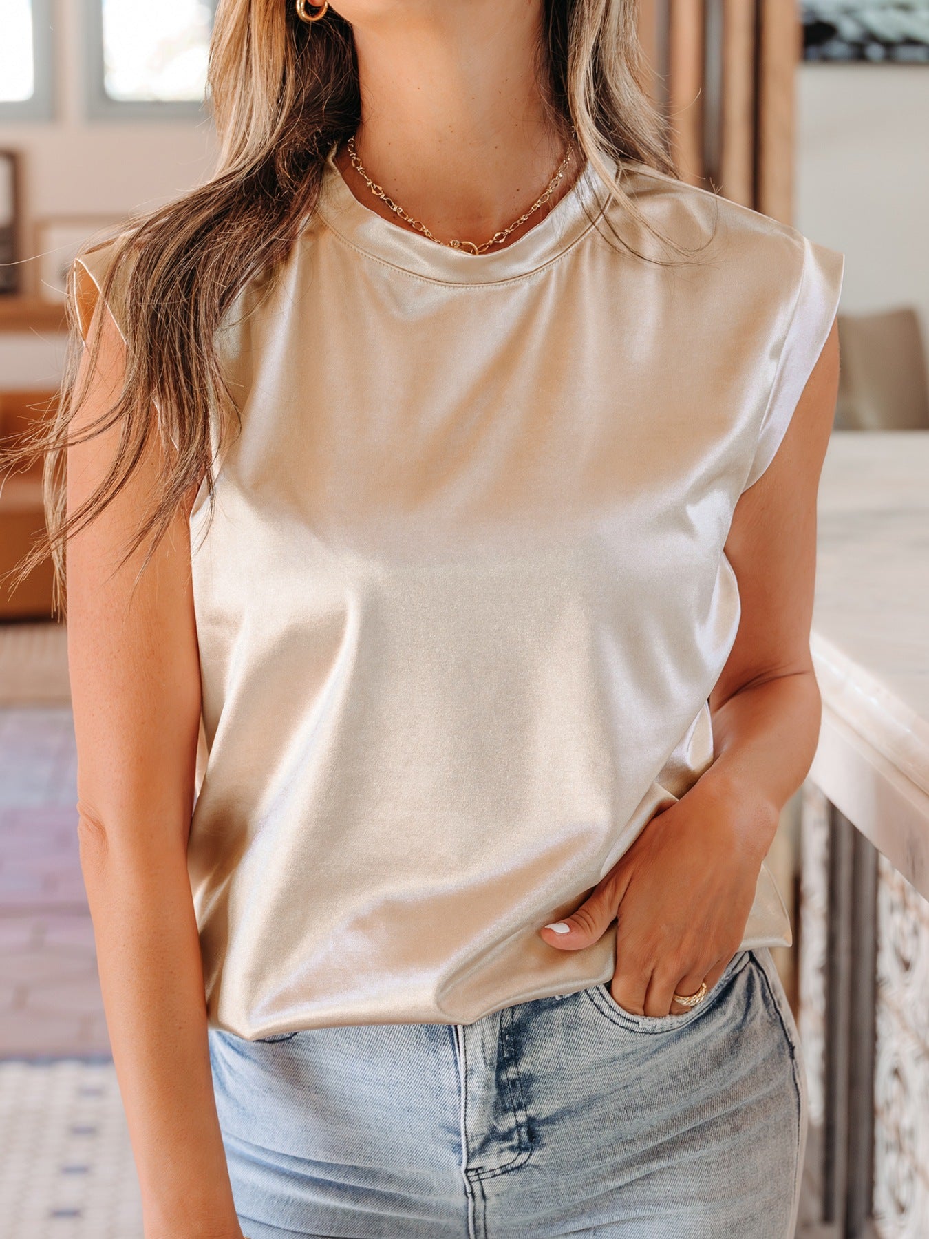 Champagne satin sleeveless tank top with shoulder pads and crew neck.