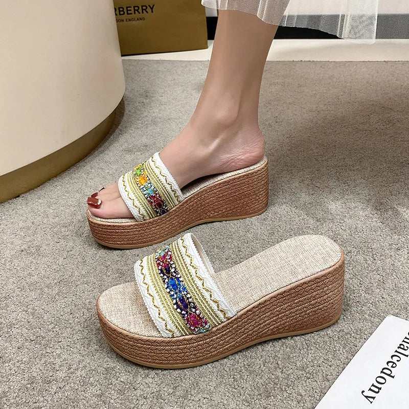 Embroidered platform wedge slides in beige with colorful floral detail and woven wedge heel.