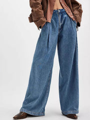 Pleated wide-leg denim trousers in dusty blue with a buttoned fly and front pockets.