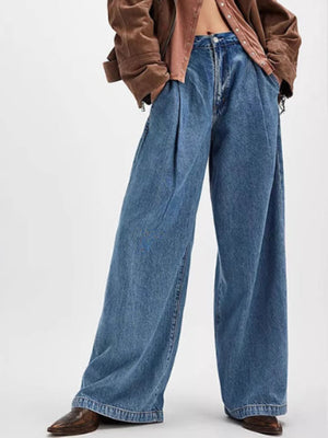 Pleated wide-leg denim trousers in dusty blue with a buttoned fly and front pockets.