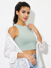 Sage high-neck crop tank top with a smooth finish, styled with a white open shirt.
