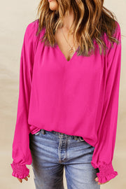 Hot pink blouse with V-neck and ruched cuffs.