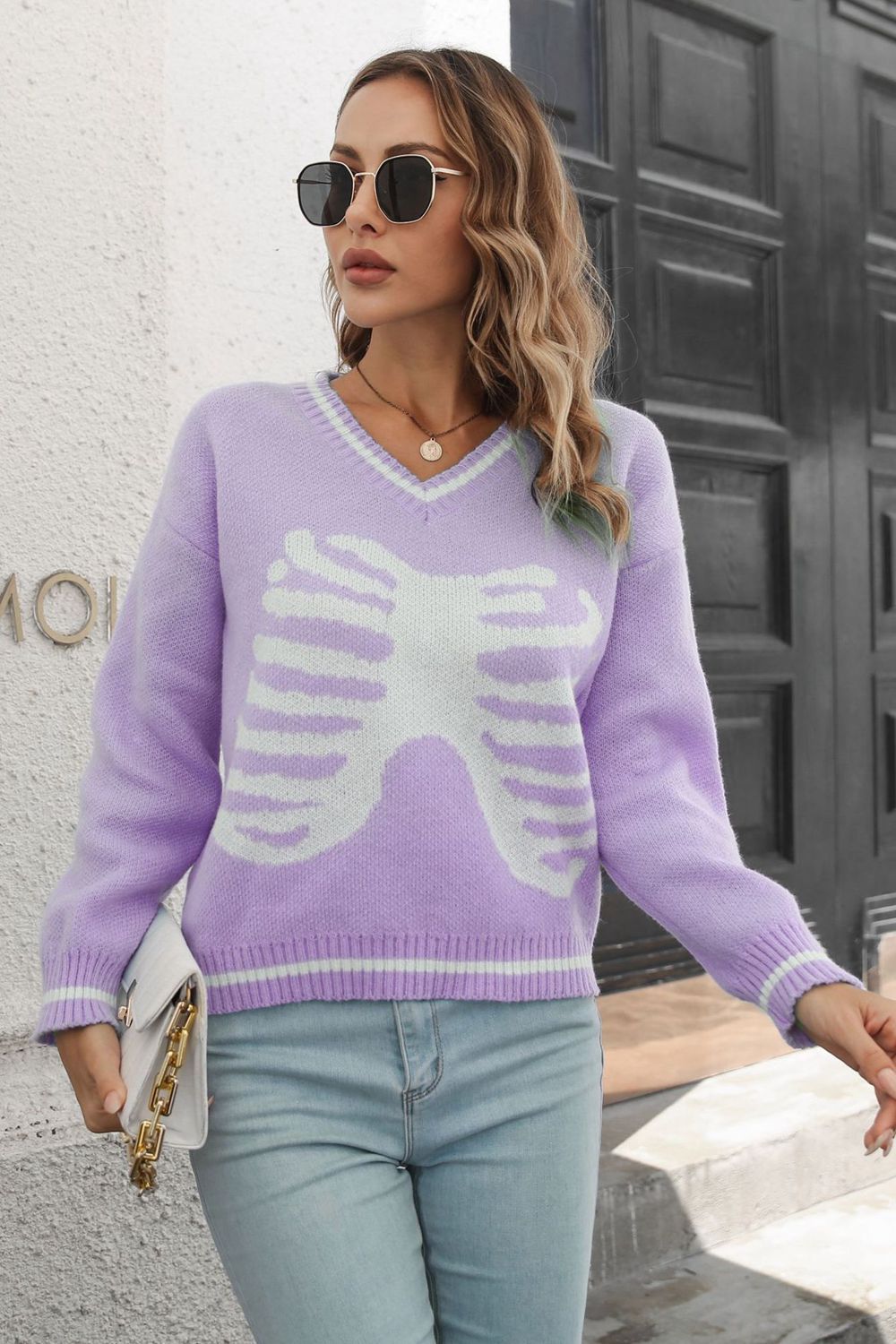 Lavender knit sweater with white ribcage graphic, v-neck, and striped cuffs.