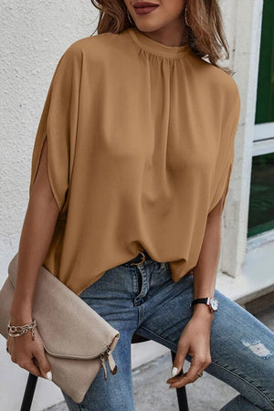 Camel blouse with drapey sleeves and mock neck, styled with jeans.