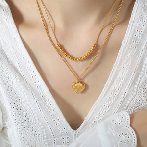 Gold layered necklace with beaded chain and checkered heart charm