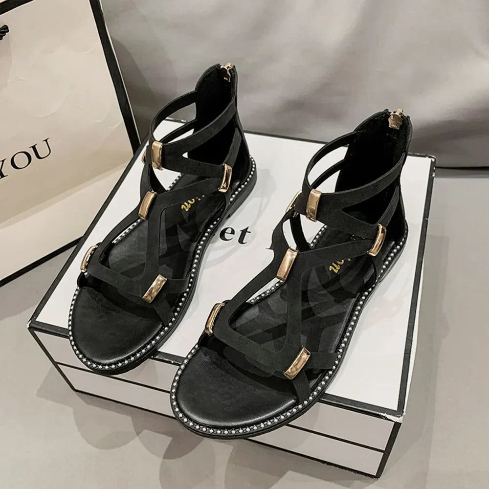 Black gladiator zip-back sandals with gold accents and strappy design.