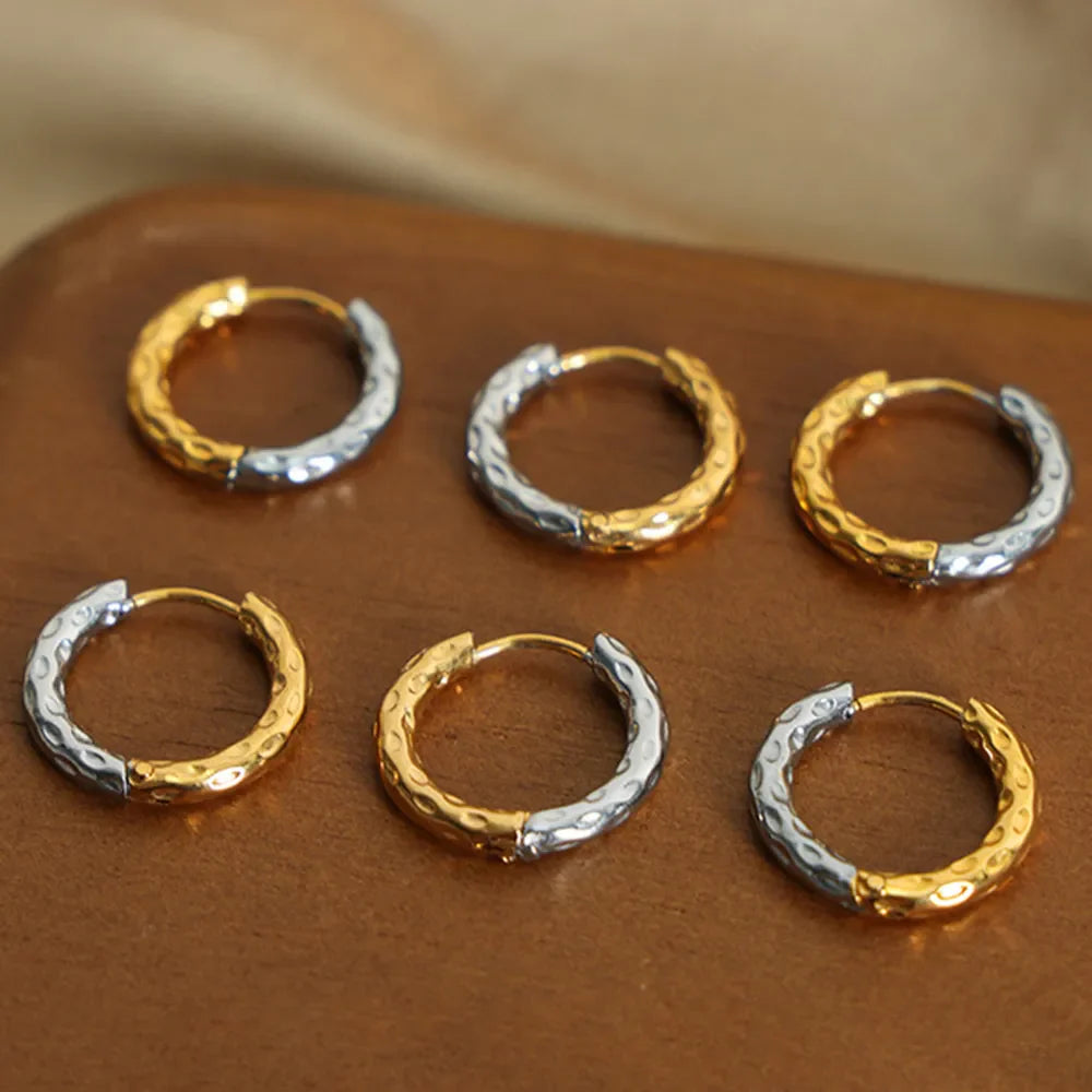 Textured two-tone huggie hoop earrings in gold and silver with a hammered finish.