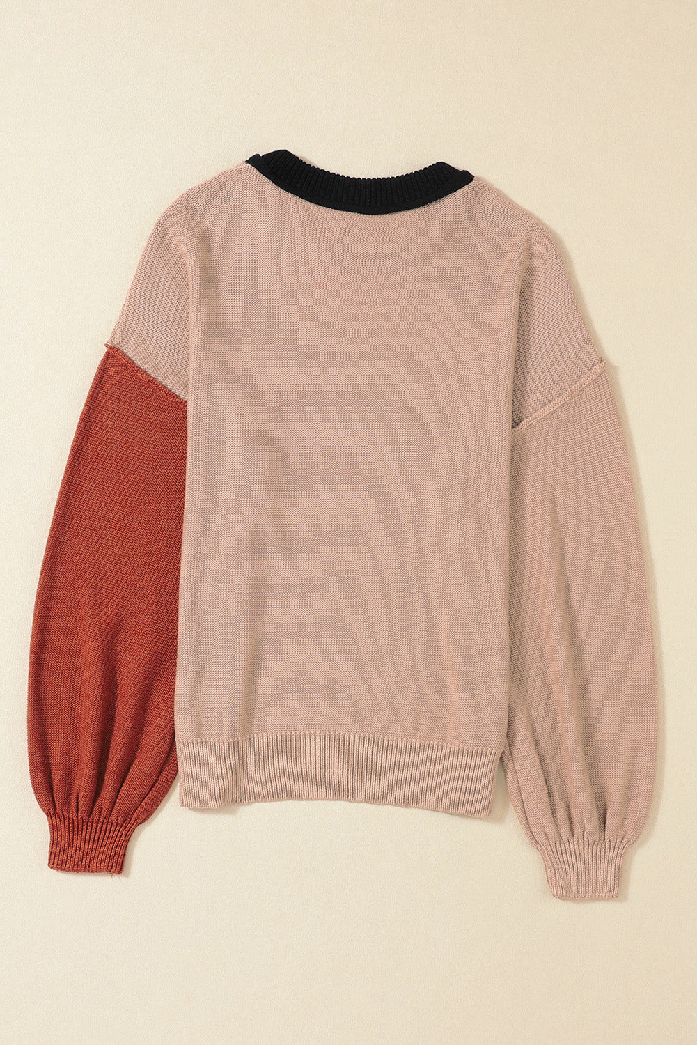 Blush pink sweater with black collar and rust balloon sleeves, ribbed cuffs and hem.