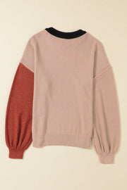 Blush pink sweater with black collar and rust balloon sleeves, ribbed cuffs and hem.