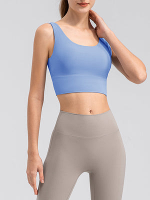 Light blue performance crop top with scoop neck and wide band, paired with taupe leggings.