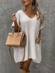 Relaxed knit tunic in white with V-neck, short sleeves, and front pockets.