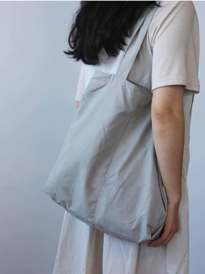 Spacious light blue nylon shoulder bag with slip pocket and contrast stitching detail.