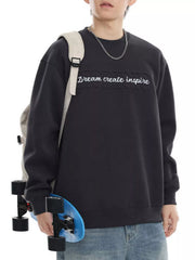 Black oversized crew-neck sweatshirt with raised "Dream create inspire" text and a cotton blend feel.