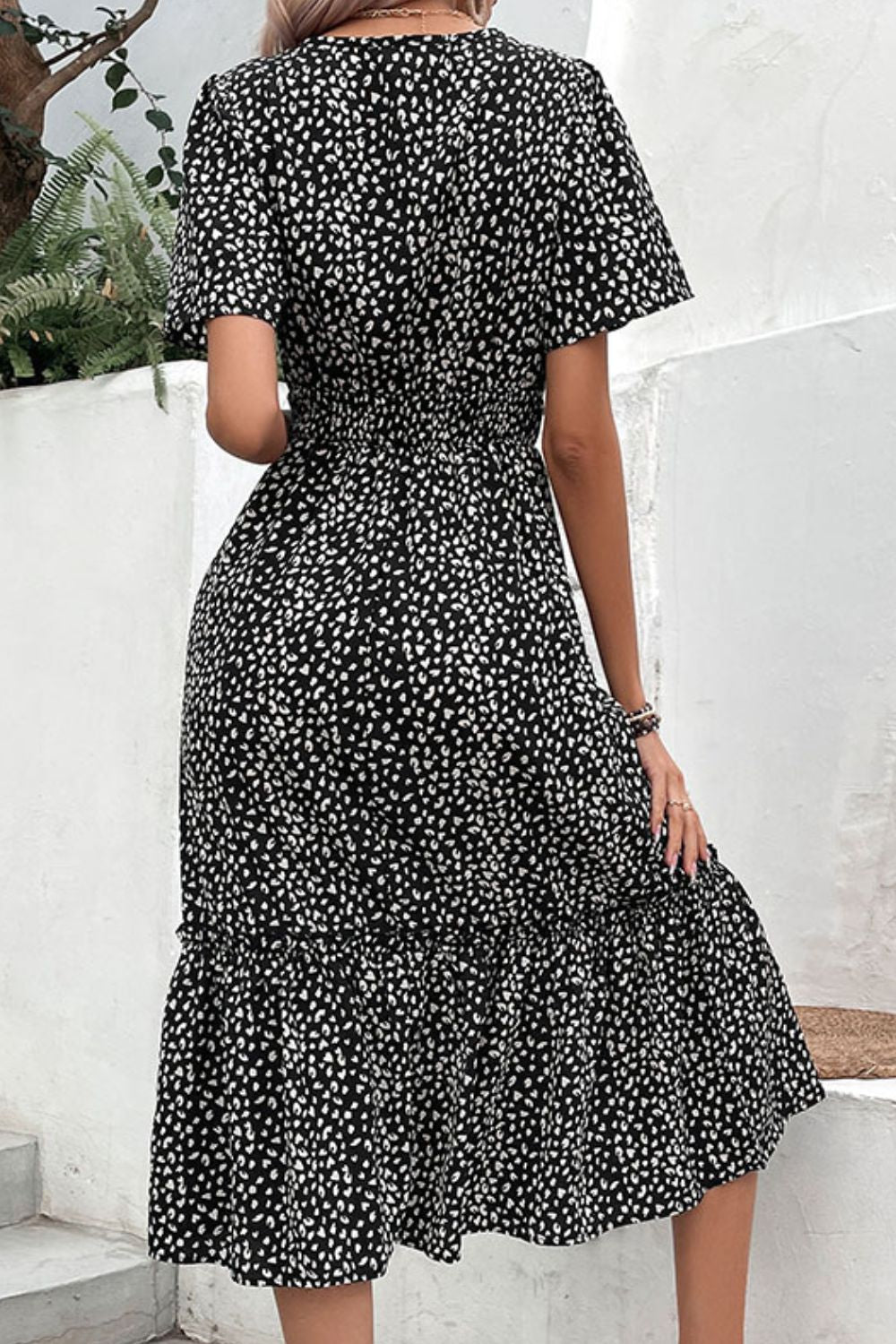 Black floral print midi dress with smocked waist and flutter sleeves.