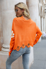 Orange acrylic sweater with daisy appliqué and distressed edges.