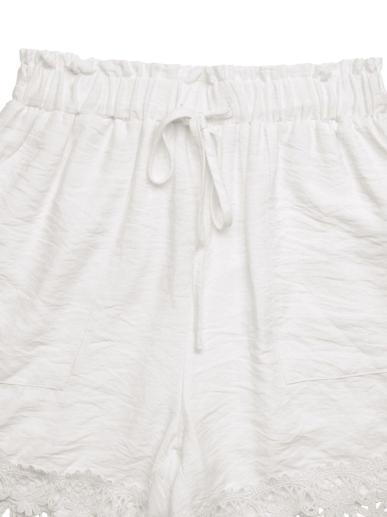 White drawstring waist shorts with lace trim and textured fabric.