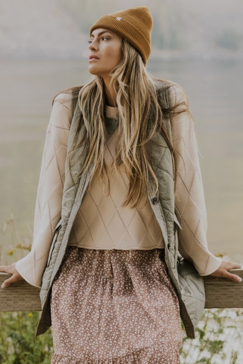 Quilted vest coat in sage with patch pockets, worn over a diamond-patterned sweater.