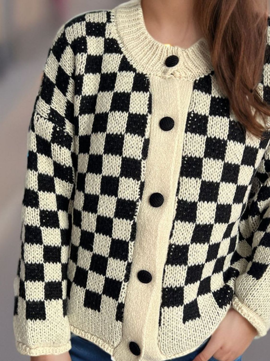 Checkerboard knit button-up cardigan in black and cream with black buttons.